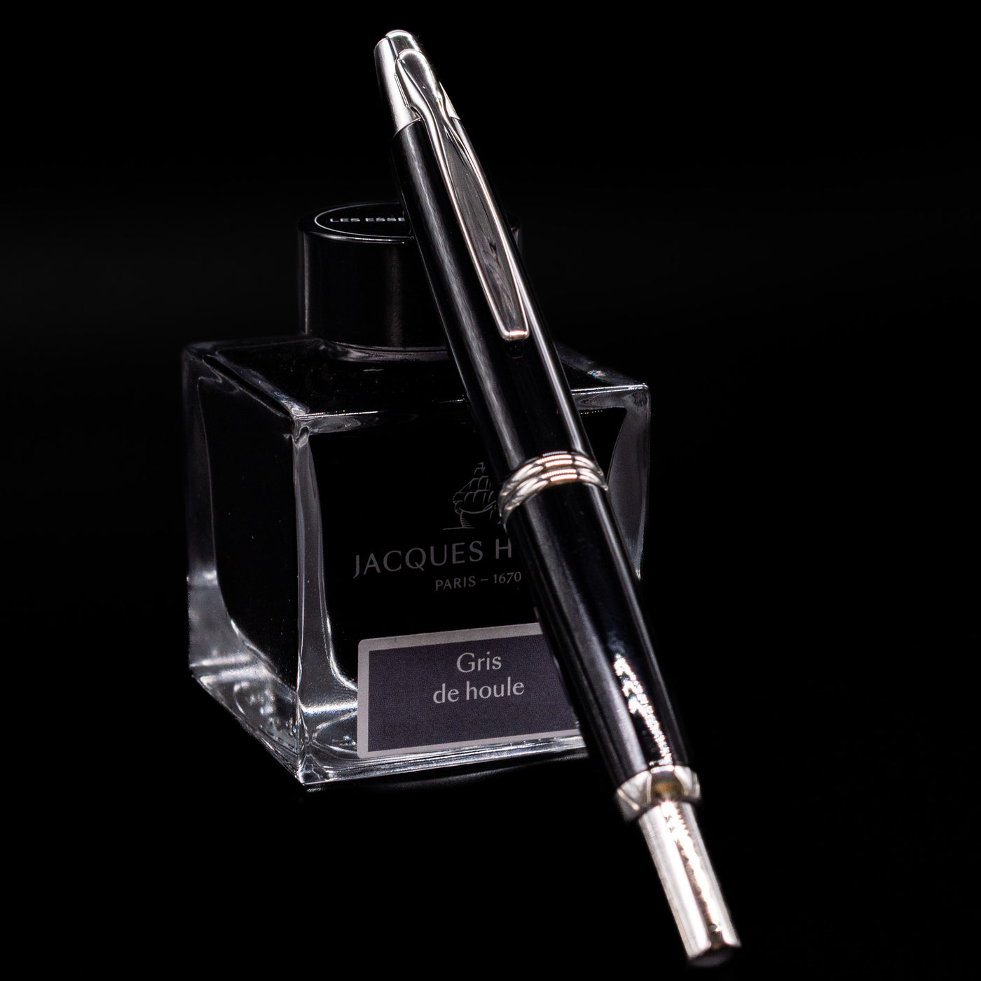 Clip side view of Pilot Vanishing Point Decimo Fountain Pen in Black and Rhodium leaning on Jacques Herbin ink bottle