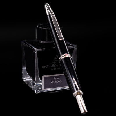 Clip side view of Pilot Vanishing Point Decimo Fountain Pen in Black and Rhodium leaning on Jacques Herbin ink bottle