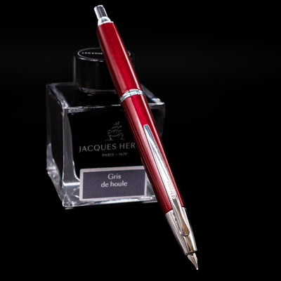 Pilot Vanishing Point Decimo Fountain Pen in Burgundy resting on Jacques Herbin Gris de Houle ink bottle with nib extended