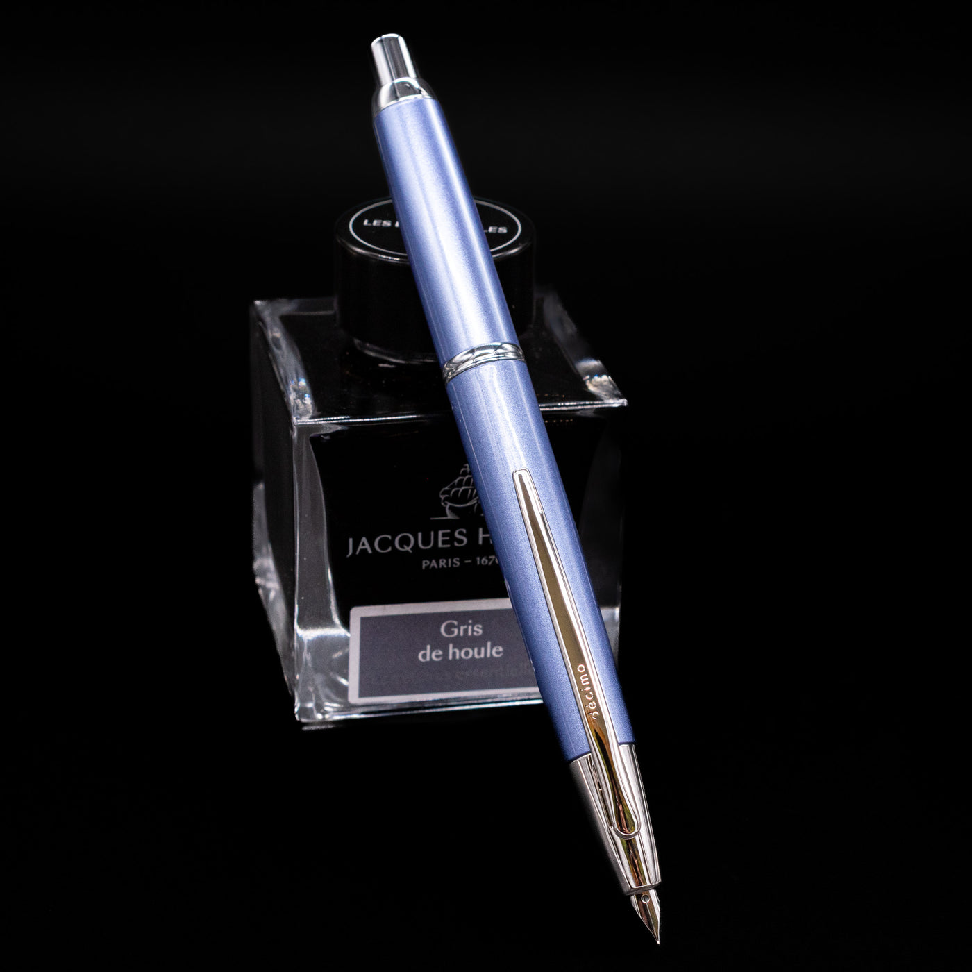 Pilot Vanishing Point Decimo Fountain Pen in Light Blue resting on Jacques Herbin Gris de Houle ink bottle with nib extended