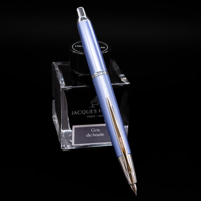 Pilot Vanishing Point Decimo Fountain Pen in Light Blue resting on Jacques Herbin Gris de Houle ink bottle with nib extended