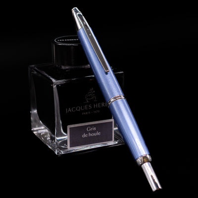 Pilot Vanishing Point Decimo Light Blue fountain pen with nib retracted, leaning on Jacques Herbin ink bottle