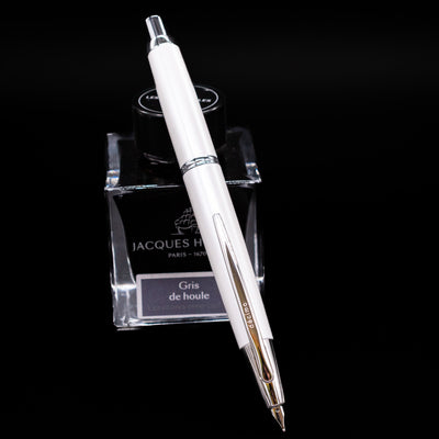 Pilot Vanishing Point Decimo Fountain Pen in White with nib extended, displayed on Jacques Herbin Gris de Houle ink bottle