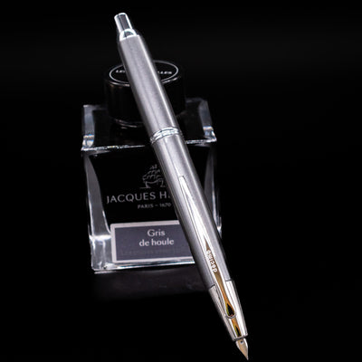 Pilot Vanishing Point Decimo Fountain Pen in Grey resting on Jacques Herbin Gris de Houle ink bottle
