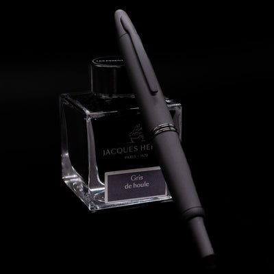 Angled view of Pilot Vanishing Point Fountain Pen in Black Matte leaning on Jacques Herbin ink bottle