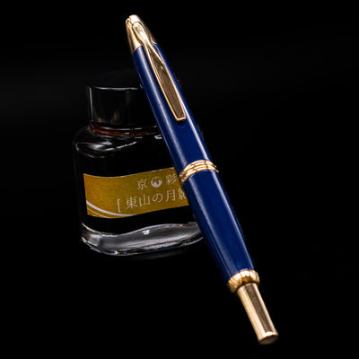 Pilot Vanishing Point Fountain Pen in Blue with Gold Trim – click-style mechanism shown with pen resting against yellow ink bottle
