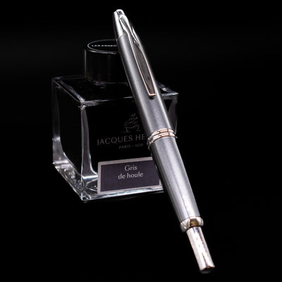 Pilot Vanishing Point Fountain Pen in Gun Metal with nib retracted, resting on Jacques Herbin Gris de Houle ink bottle