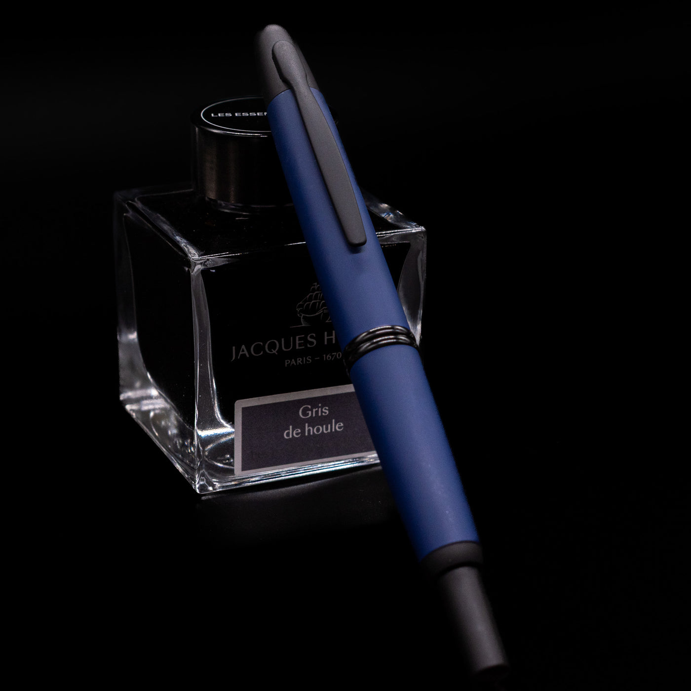 Pilot Vanishing Point Fountain Pen Matte Blue with cap fully extended, resting on Jacques Herbin Gris de Houle ink bottle.