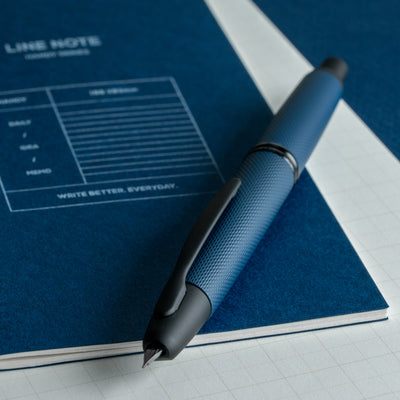 Pilot Vanishing Point Limited Edition 2025 Fountain Pen Midnight Link resting on a blue lined notebook, emphasizing the pen’s textured grip and luxury appeal.