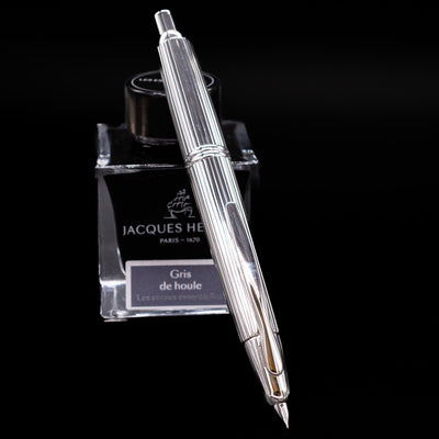 Pilot Vanishing Point Stripes Fountain Pen standing upright on Jacques Herbin ink bottle