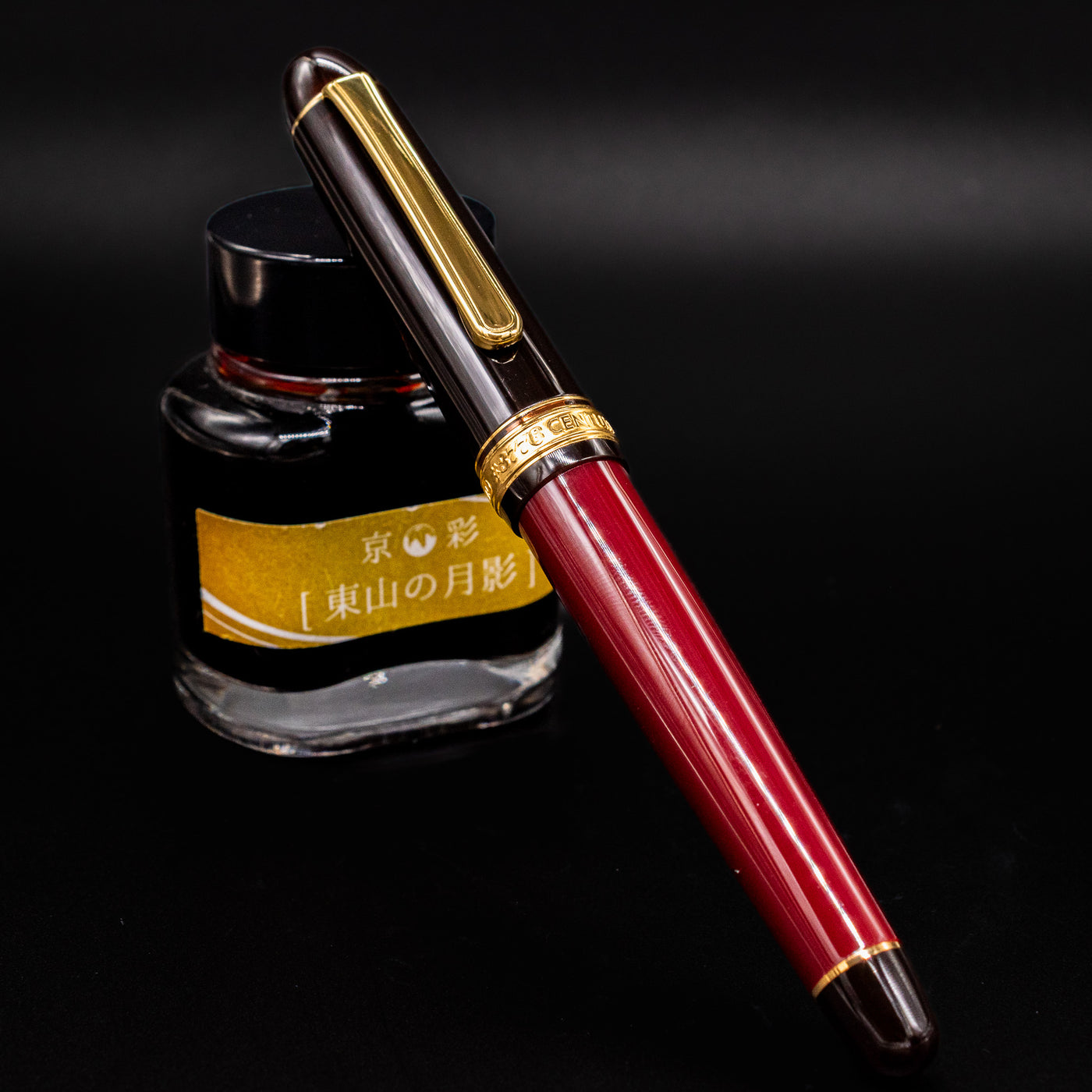 Platinum 3776 Century Fountain Pen in Coffee Jelly color capped and resting on ink bottle with gold trim