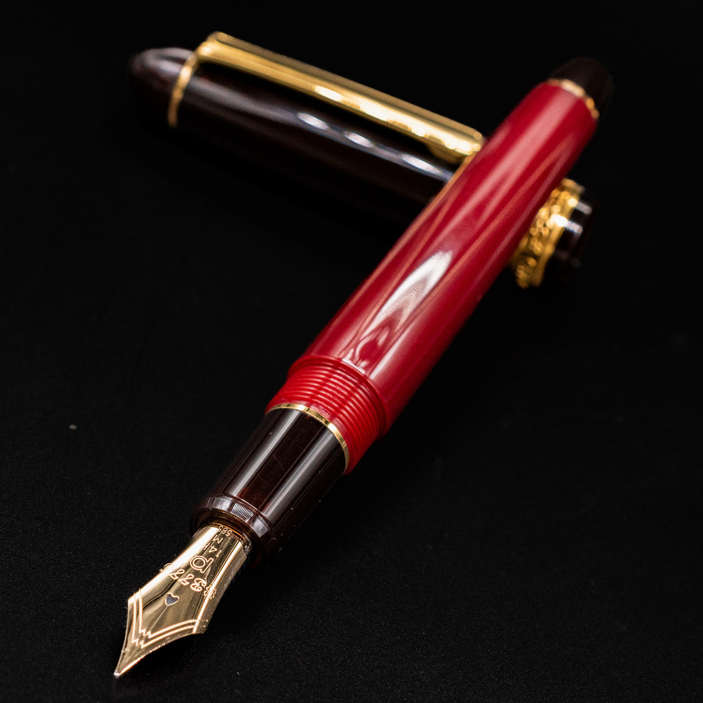 Close-up of the Platinum 3776 Century Fountain Pen gold nib and red barrel with brown section and cap in background