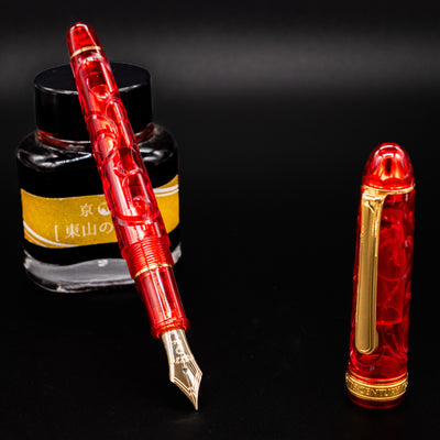 Platinum 3776 Century Kinshu Fountain Pen with red swirled resin body shown next to Kyo no Oto ink bottle