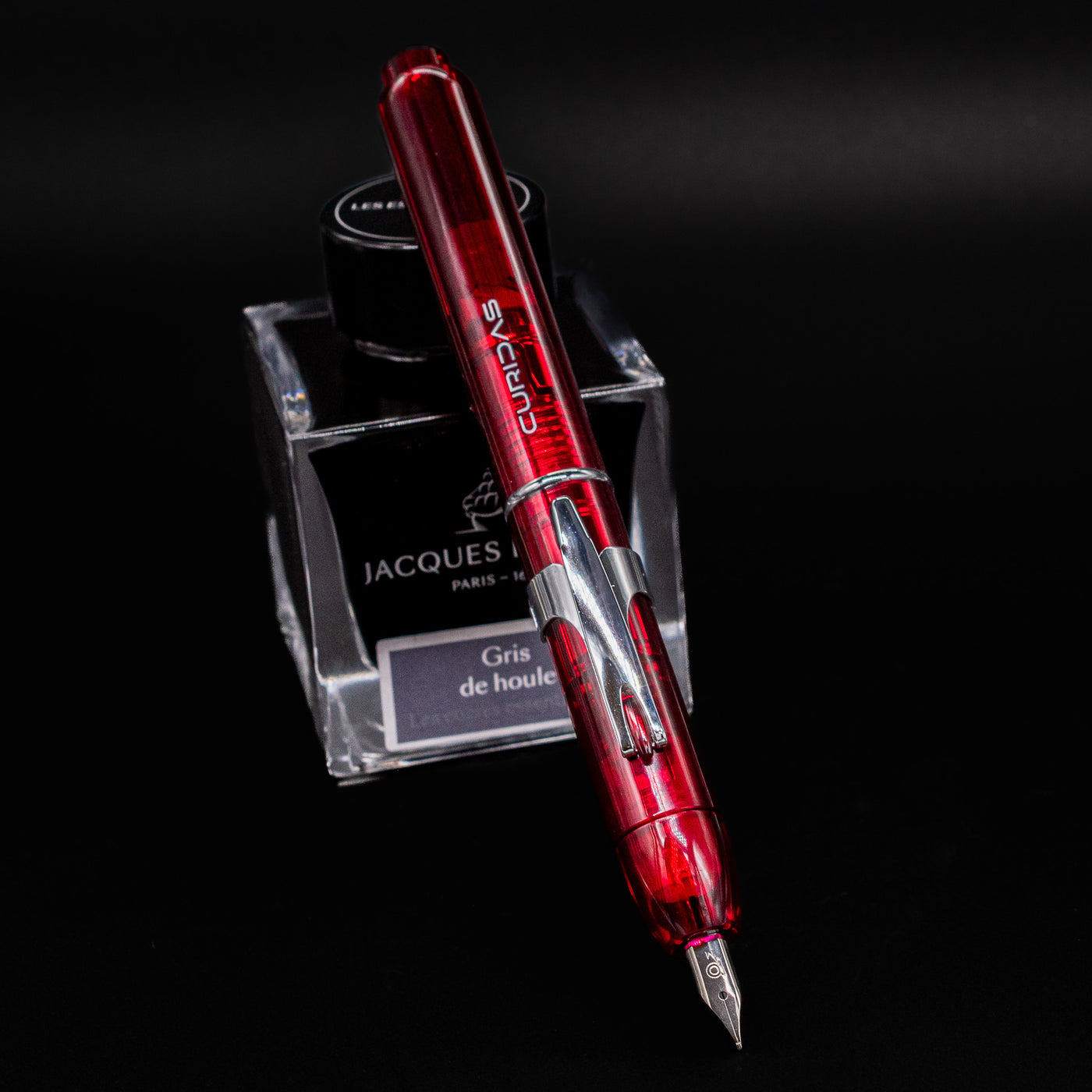 Platinum Curidas Fountain Pen in Gran Red color angled on Jacques Herbin Gris de Houle ink bottle