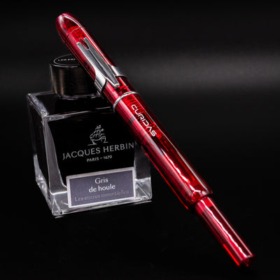 Side view of Platinum Curidas Gran Red Fountain Pen displayed on Jacques Herbin ink bottle