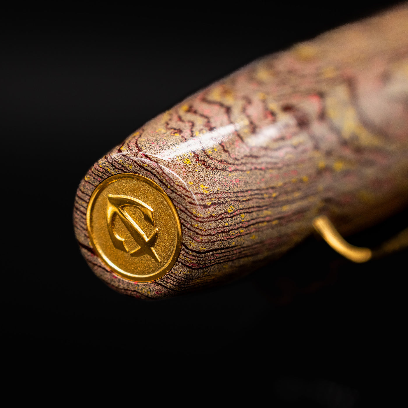Close-up of the Sailor King of Pens Naginata Togi Syokei Ebonite Fountain Pen cap finial, showing the gold anchor emblem set against a marbled brown ebonite pattern.