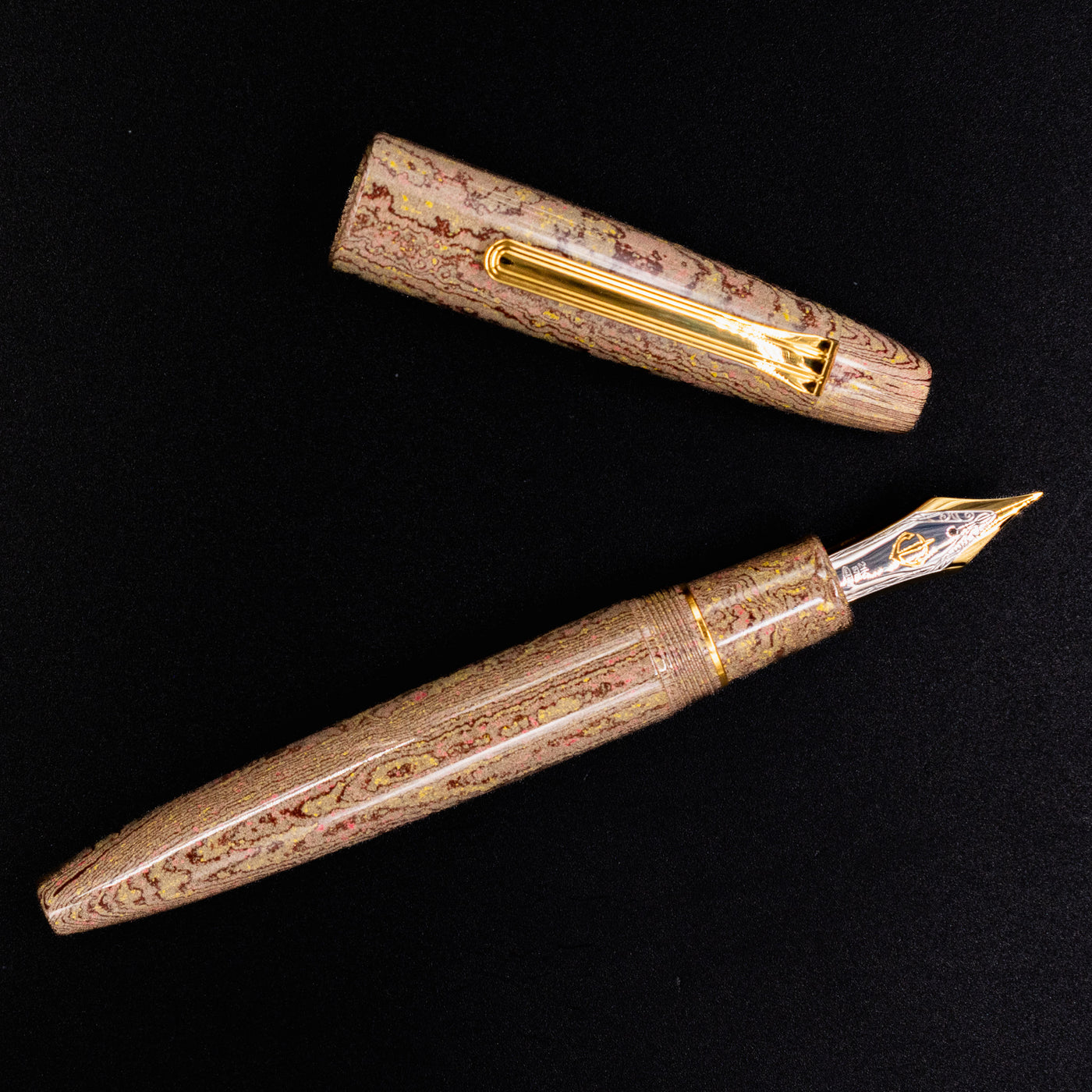 Flat lay of the Sailor King of Pens Naginata Togi Syokei Ebonite Fountain Pen with the cap removed, revealing the 21k gold nib and swirling brown ebonite texture.