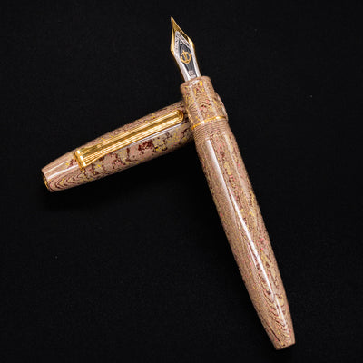 Sailor King of Pens Naginata Togi Syokei Ebonite Fountain Pen shown open with nib facing up, highlighting the marbled ebonite body and gold trim on a black background.