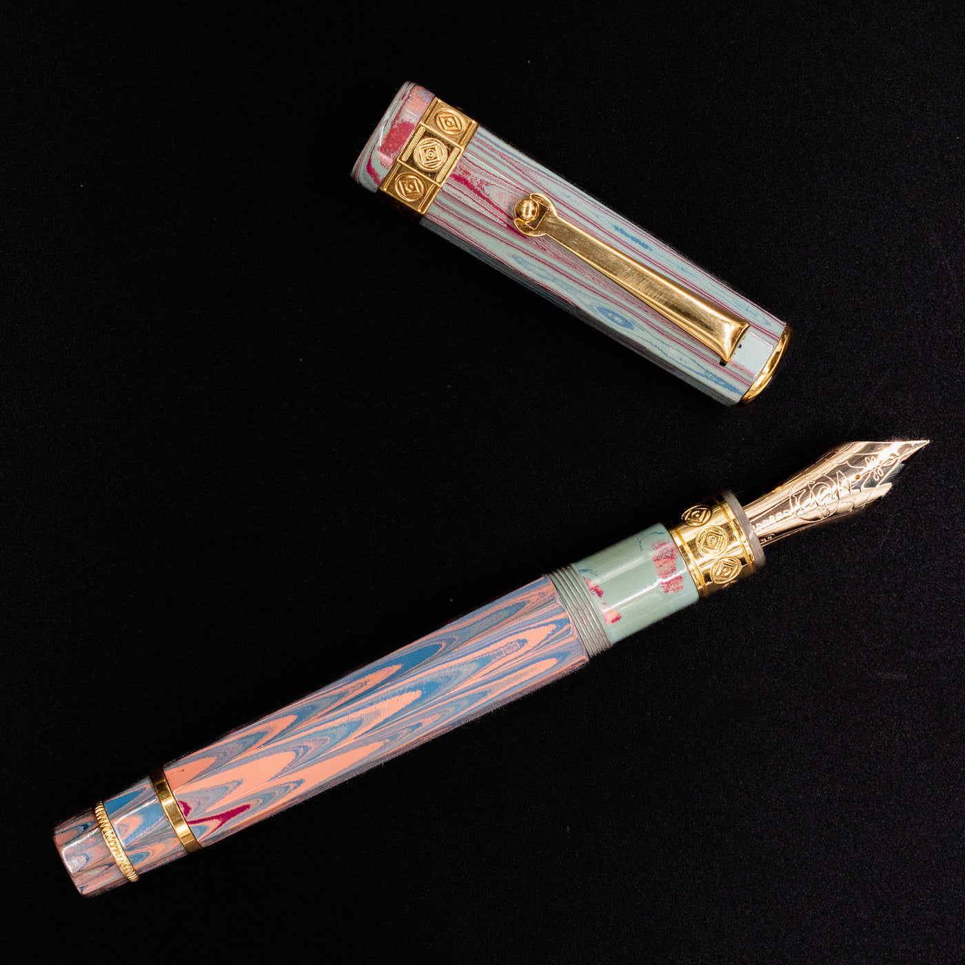 Flat lay of the Santini Giant 8 Faceted Burano Fountain Pen with the cap removed, showcasing the pastel marbled resin and detailed gold nib against a black background.