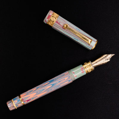 Flat lay of the Santini Giant 8 Faceted Burano Fountain Pen with the cap removed, showcasing the pastel marbled resin and detailed gold nib against a black background.