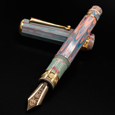 Santini Giant 8 Faceted Burano Fountain Pen with gold nib exposed and cap resting behind, showcasing intricate marbled resin and ornate gold trim.