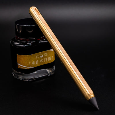Stilform AEON Pencil Brass with Maple Veneer - leaning on ink bottle