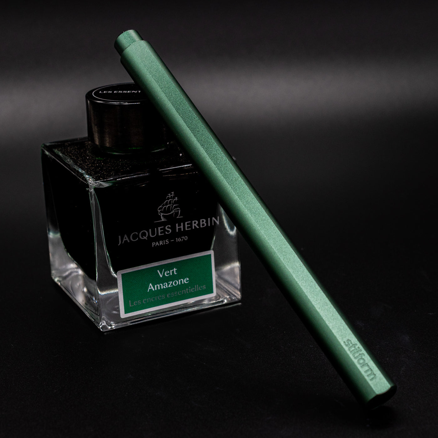 Stilform FLOW Rollerball Pen Aurora Green - capped and leaning on ink bottle