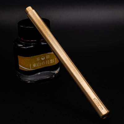 Stilform FLOW Rollerball Pen Brass Radial Brushed - capped and leaning on ink bottle