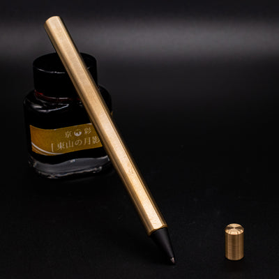 Stilform FLOW Rollerball Pen Brass Radial Brushed - uncapped and leaning on ink bottle