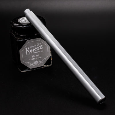 Stilform FLOW Rollerball Pen Comet Grey- capped and leaning on ink bottle