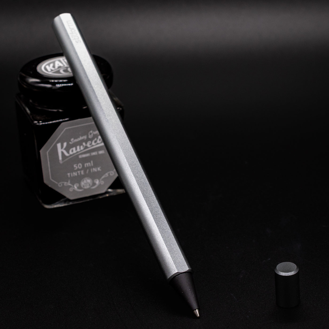 Stilform FLOW Rollerball Pen Comet Grey- uncapped and leaning on ink bottle