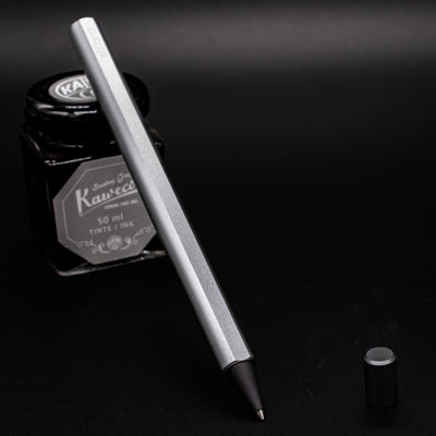 Stilform FLOW Rollerball Pen Comet Grey- uncapped and leaning on ink bottle
