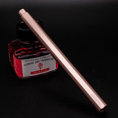 Stilform FLOW Rollerball Pen Rose Moon Aluminum - capped and leaning on ink bottle