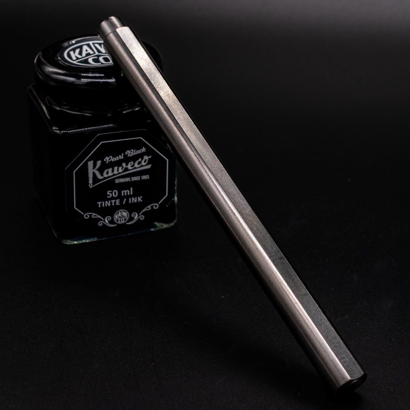 Stilform FLOW Rollerball Pen Titanium DLC - capped and leaning on ink bottle