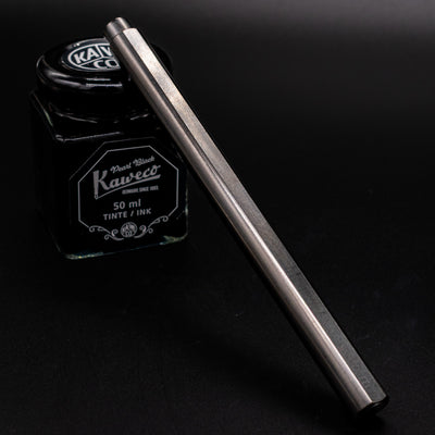 Stilform FLOW Rollerball Pen Titanium DLC - capped and leaning on ink bottle