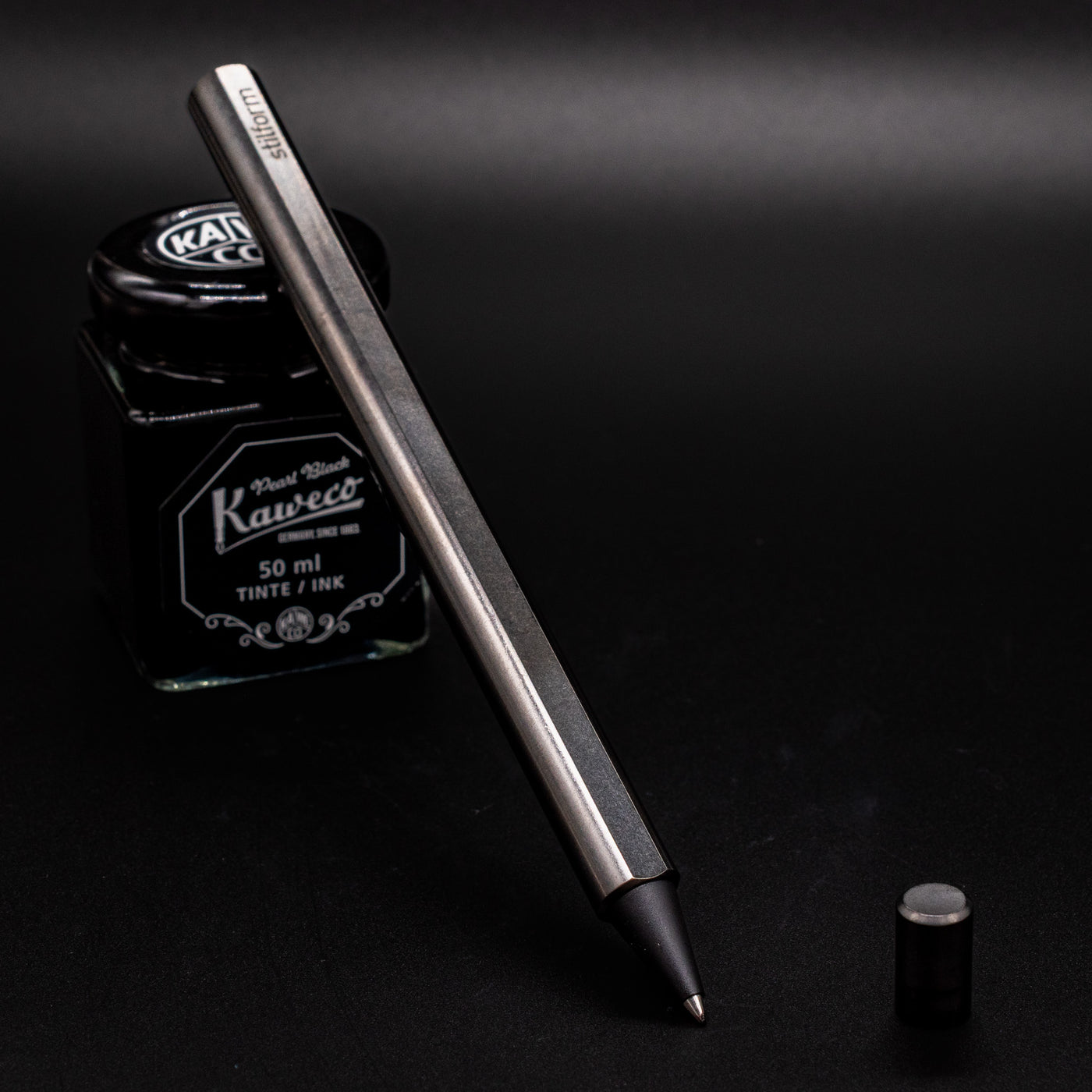 Stilform FLOW Rollerball Pen Titanium DLC - Uncapped and leaning on ink bottle
