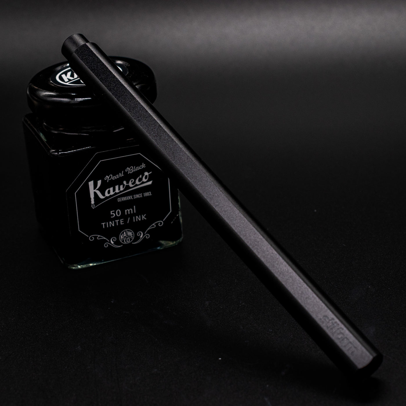 Stilform FLOW Rollerball Pen Warp Black - capped and leaning on ink bottle