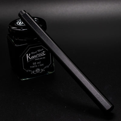 Stilform FLOW Rollerball Pen Warp Black - capped and leaning on ink bottle