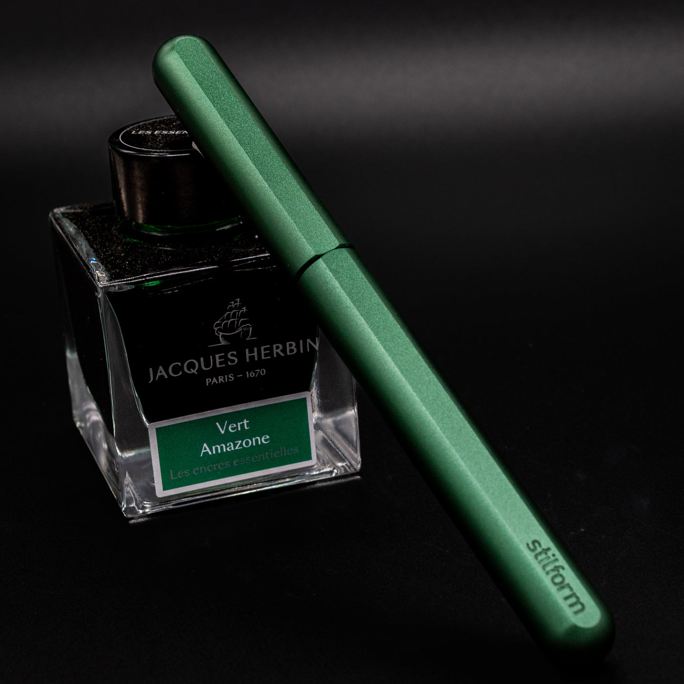 Stilform INK Fountain Pen Aurora Green – capped and leaning on ink bottle