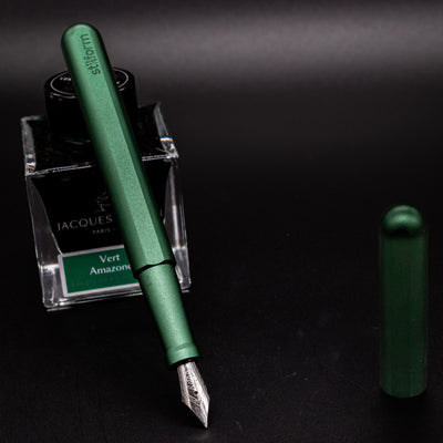 Stilform INK Fountain Pen Aurora Green – uncapped and leaning on ink bottle