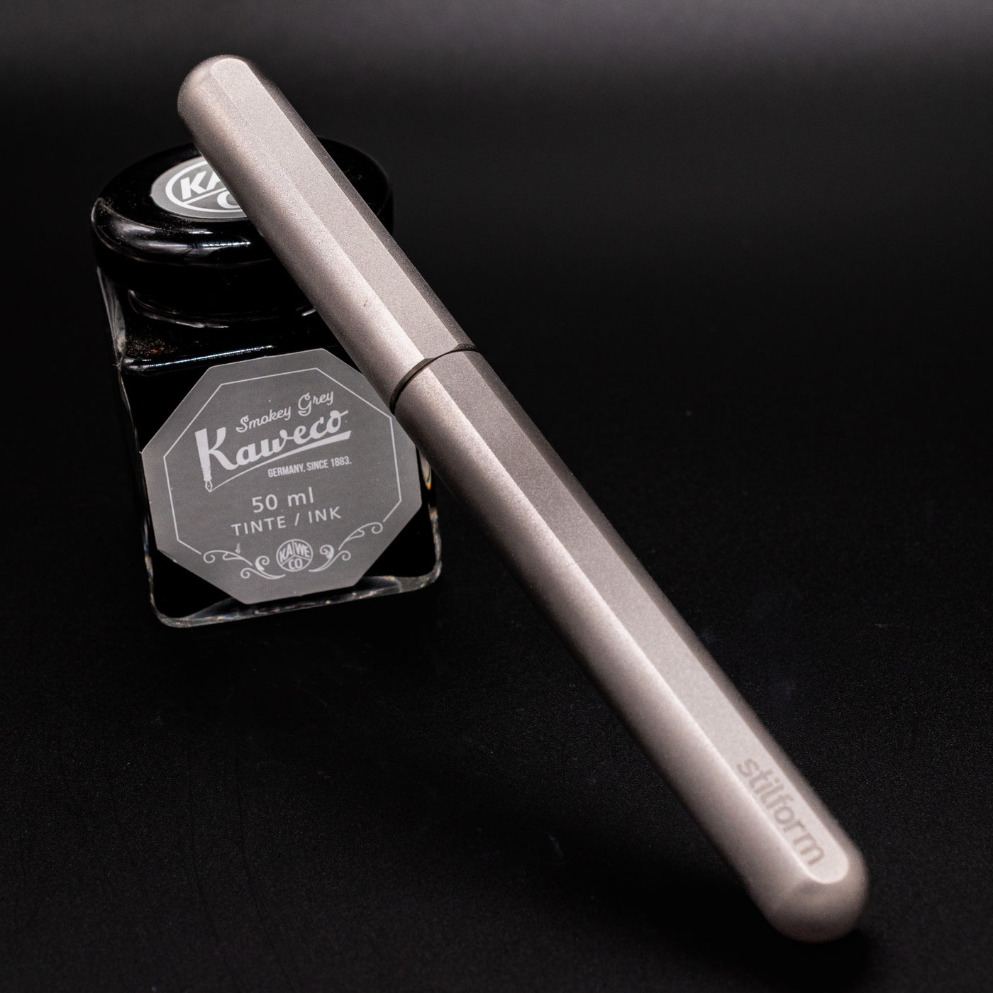 Stilform INK Fountain Pen Comet Grey – capped and leaning on ink bottle