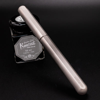 Stilform INK Fountain Pen Comet Grey – capped and leaning on ink bottle