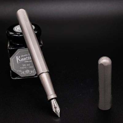 Stilform INK Fountain Pen Comet Grey – uncapped and leaning on ink bottle