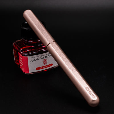 Stilform INK Fountain Pen Rose Moon Aluminum – capped and leaning on ink bottle