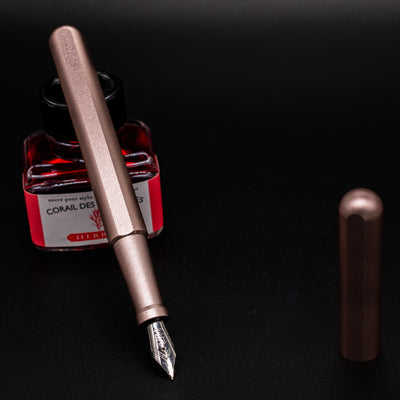 Stilform INK Fountain Pen Rose Moon Aluminum – uncapped and leaning on ink bottle