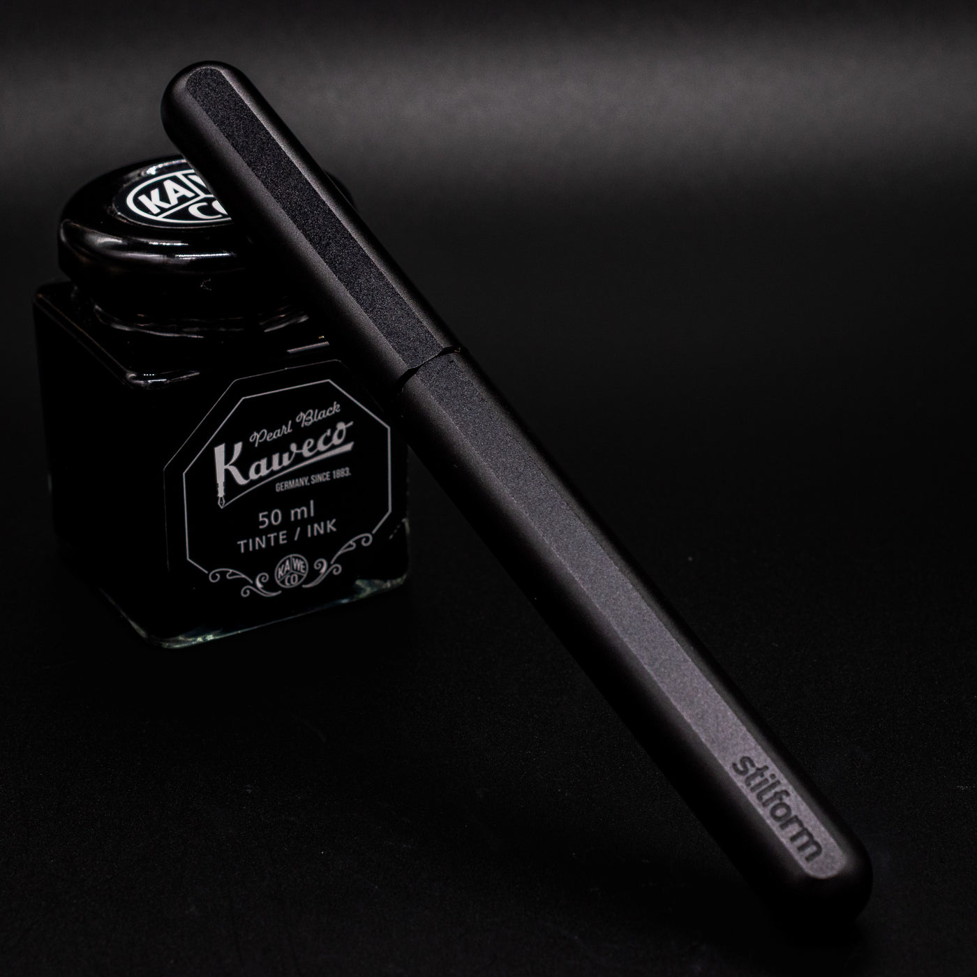 Stilform INK Fountain Pen Titanium DLC – capped and leaning on ink bottle
