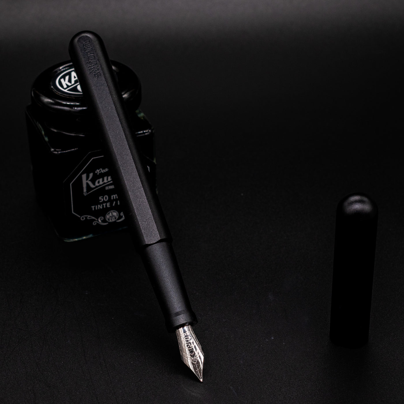 Stilform INK Fountain Pen Titanium DLC – uncapped and leaning on ink bottle