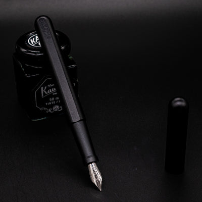 Stilform INK Fountain Pen Titanium DLC – uncapped and leaning on ink bottle
