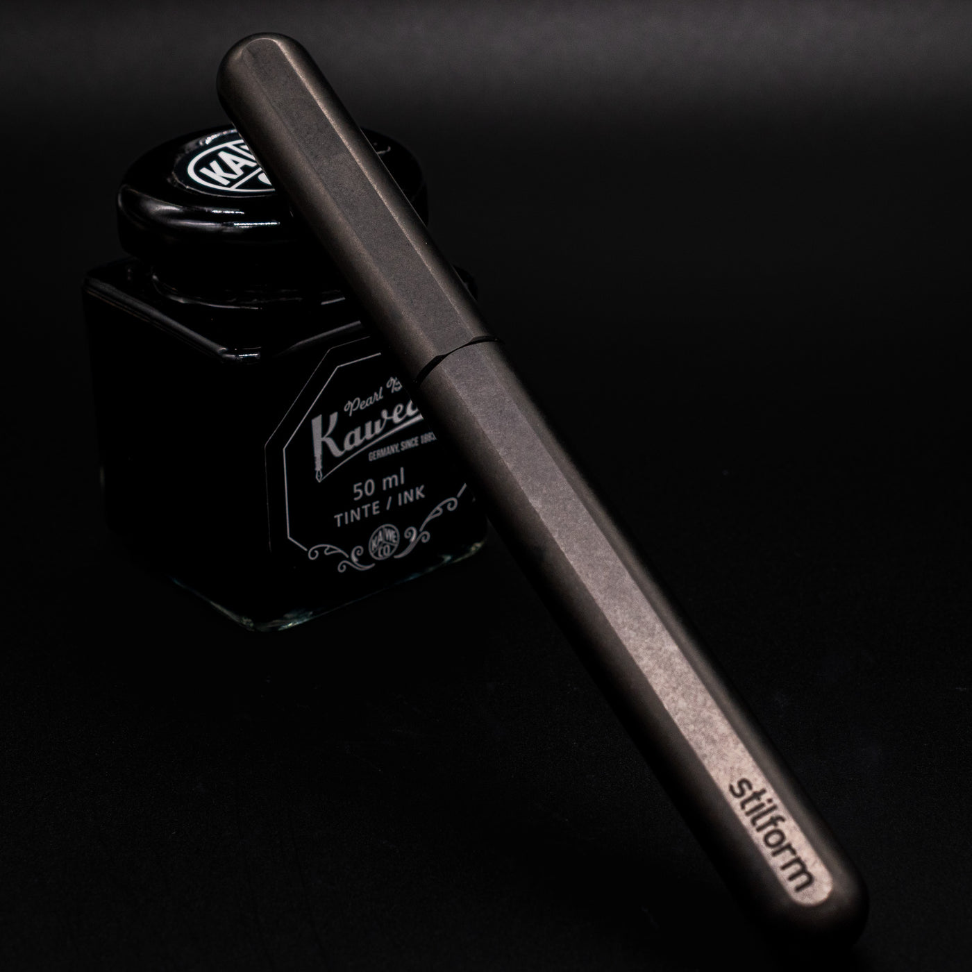 Stilform INK Fountain Pen Titanium Matte – capped and leaning on ink bottle