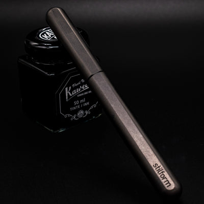 Stilform INK Fountain Pen Titanium Matte – capped and leaning on ink bottle